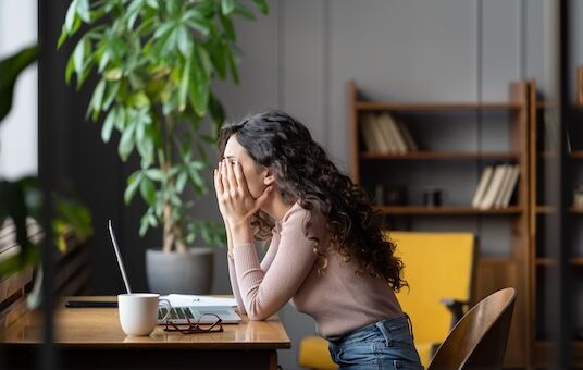 Junge Frau sitzt müde im Home-Office vor dem Laptop – Konzentrationsprobleme bei der Arbeit