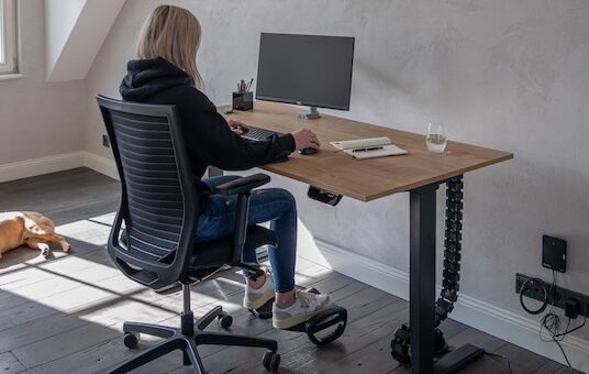 Eine junge Frau sitzt am Schreibtisch.
