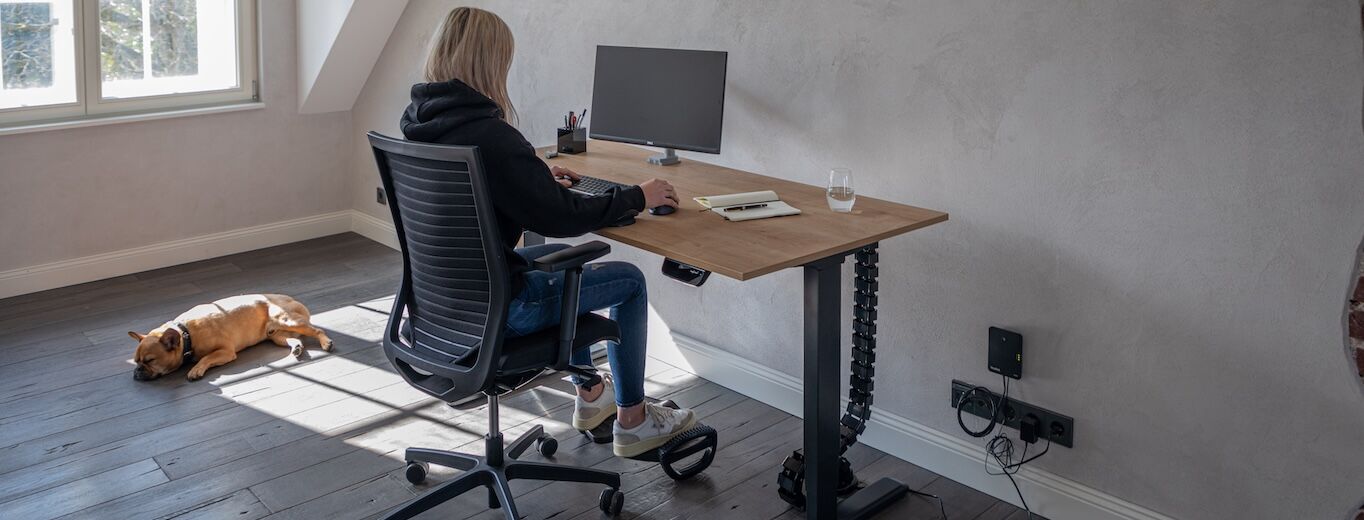 Eine junge Frau sitzt an ihrem platzsparenden Schreibtisch und arbeitet.